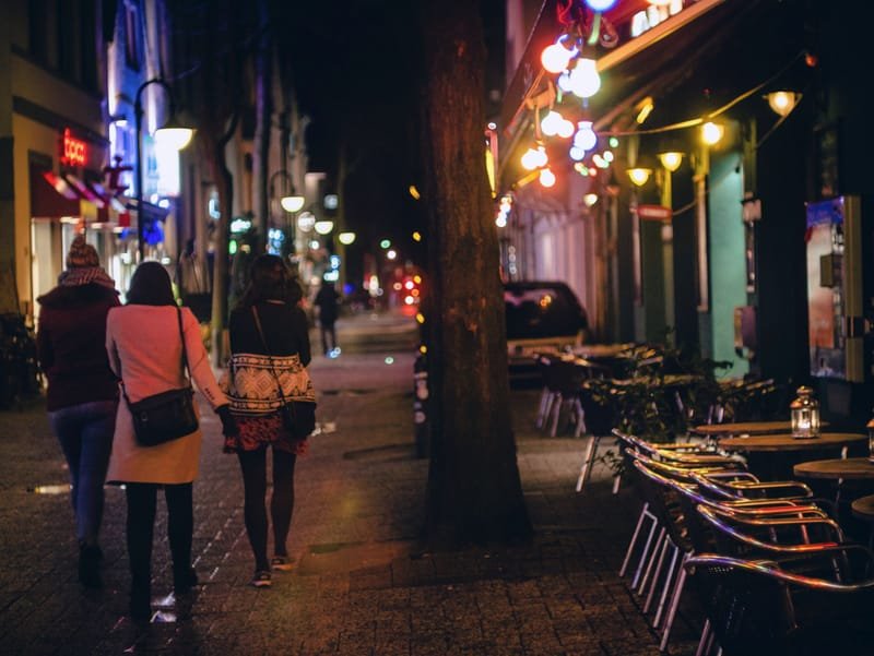 Three people in evening dress walking together down a lit night street