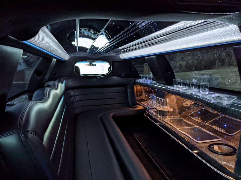Cabin with perimeter leather seating, cove lighting along the ceiling and a stocked bar rail