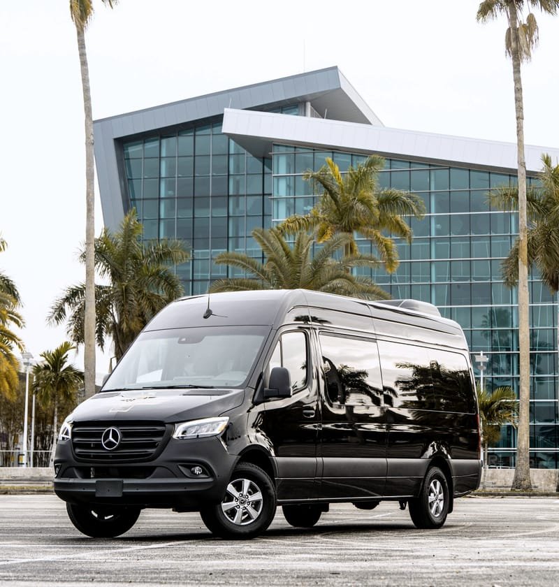 Black high-roof Mercedes-Benz Sprinter van parked outside a glass building